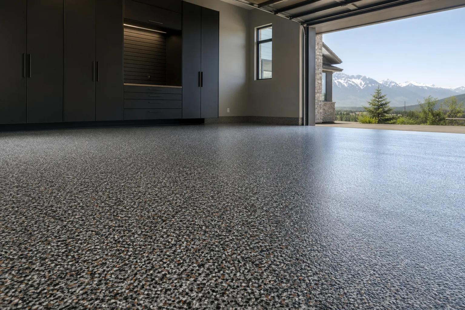 Speckled charcoal garage floor with black storage cabinets and an open mountain view